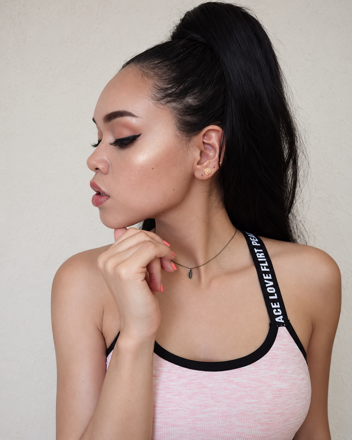Side-profile beauty portrait of Rosi Ross featuring sharp black winged eyeliner, long lashes, contoured cheekbones, and soft pink nude lips, with makeup by Rina Kozireva inspired by Ariana Grande.