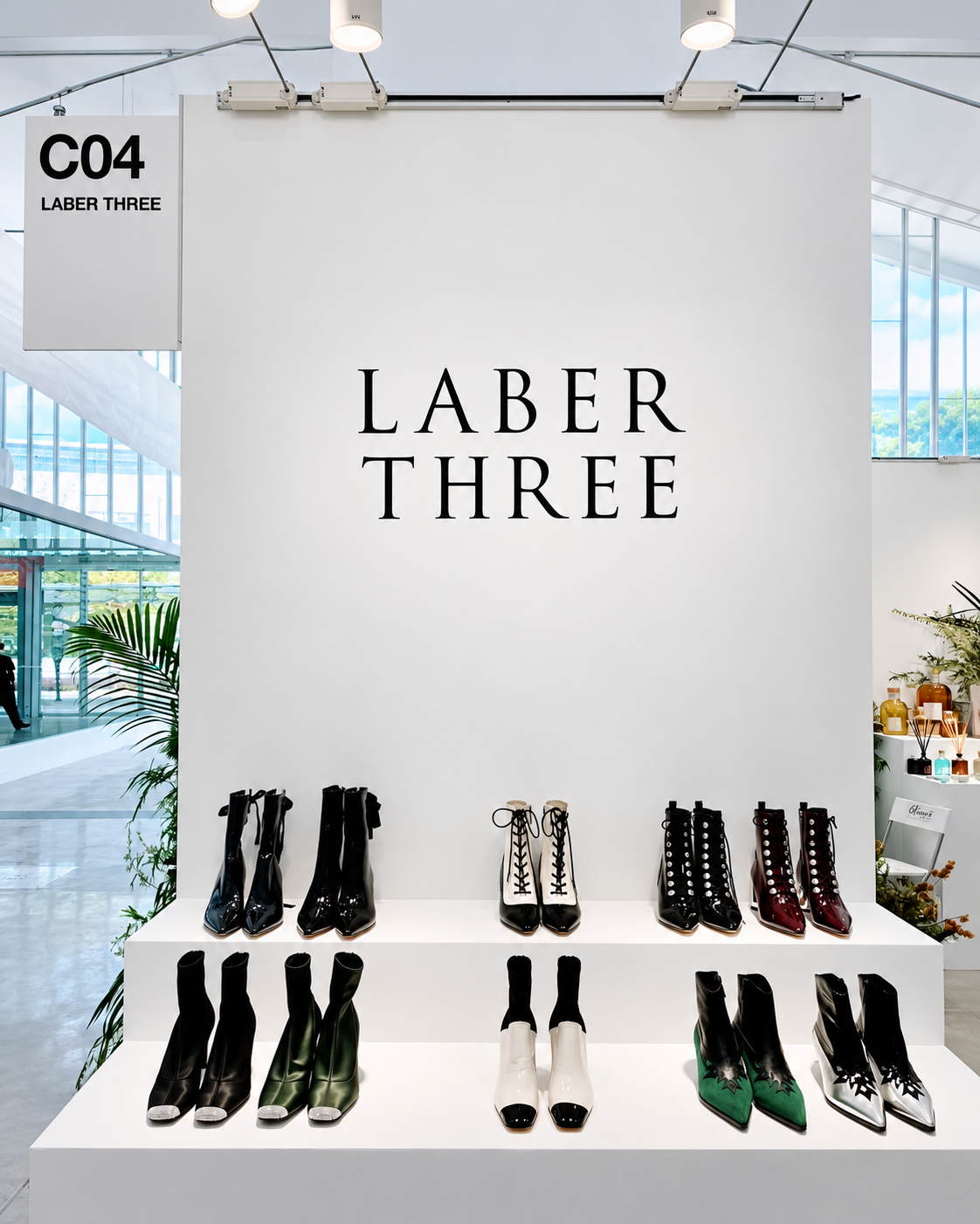 LABER THREE footwear exhibition at Ontimeshow during Shanghai Fashion Week, featuring a minimalist white display with contemporary boots and shoes arranged beneath the brand logo.