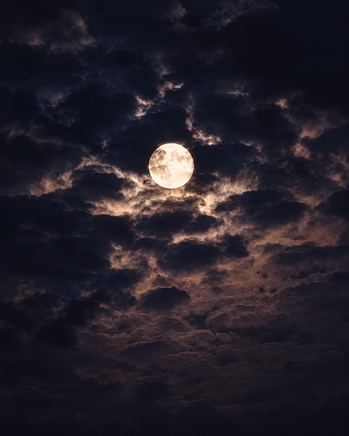 Full moon illuminating a cloudy night sky, symbolizing Rosi Ross&rsquo;s exploration of spirituality, lunar symbolism, mindfulness, and inner peace.