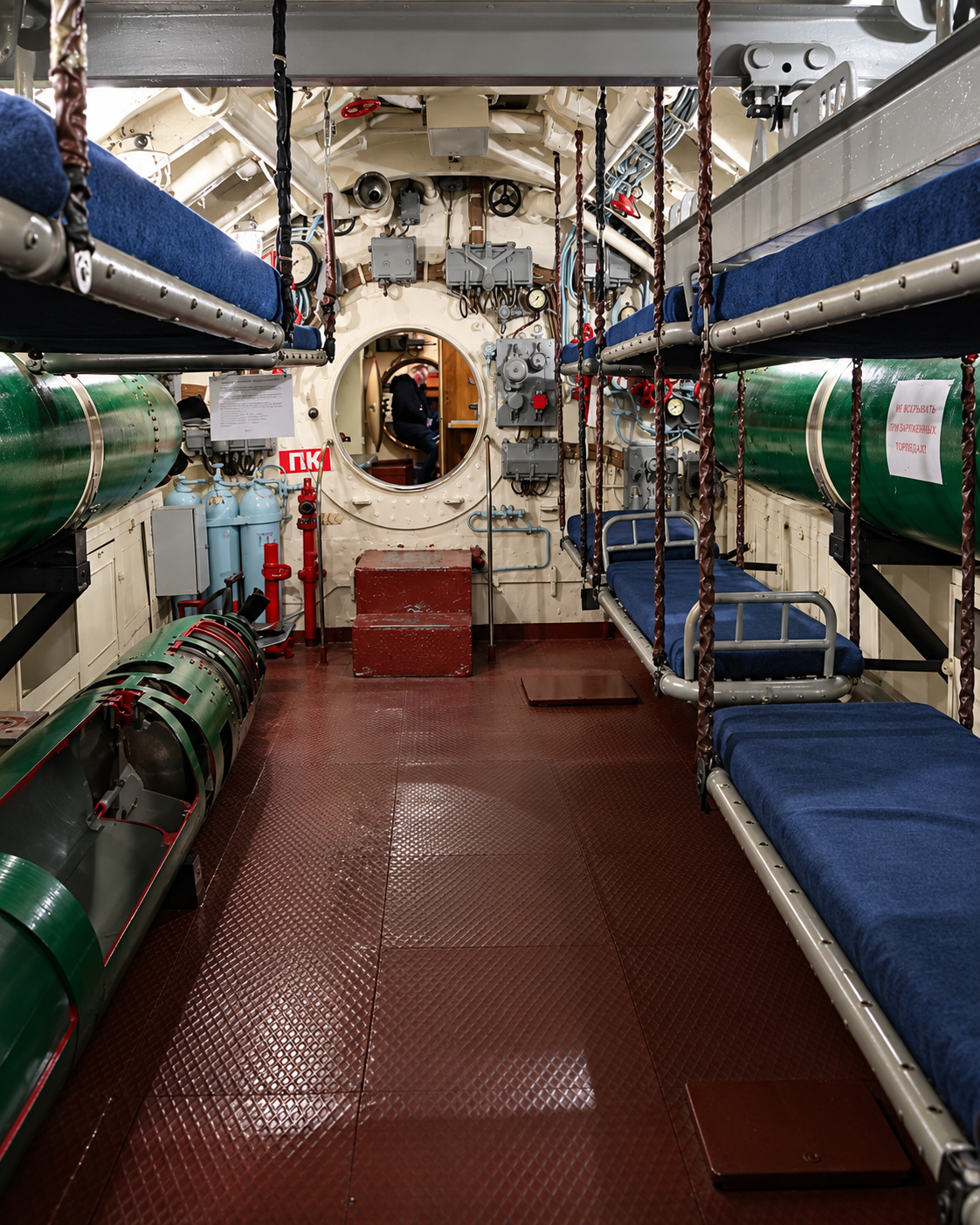 Interior compartment of the C-56 submarine in Vladivostok showing torpedo equipment, narrow passageways, and crew bunk areas.