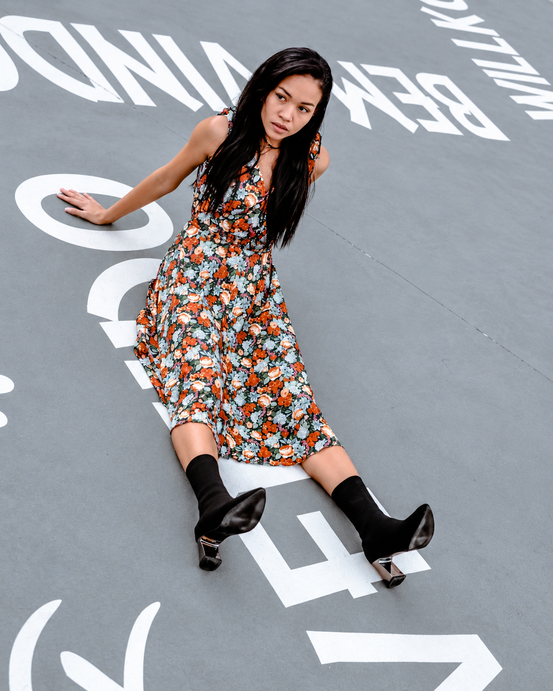 Rosi Ross wearing a colorful floral vintage dress and black ankle boots during a fashion photoshoot at a modern museum.