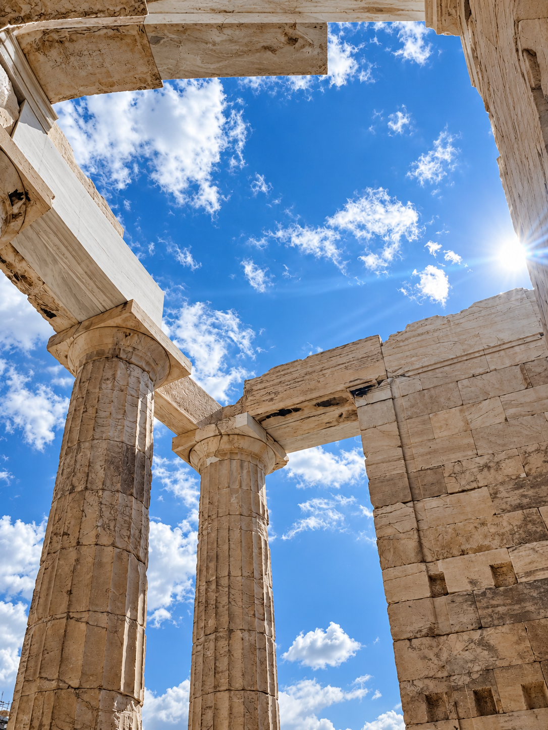 Ancient marble columns of the Parthenon at the Acropolis of Athens against a bright blue sky.