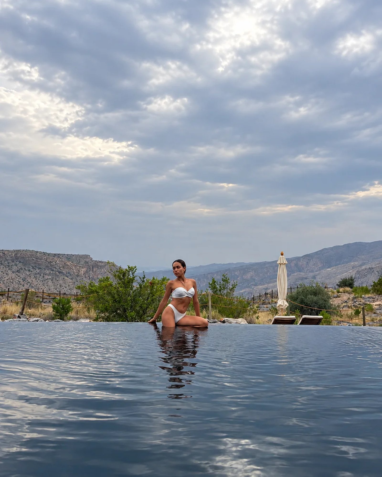 Alila Jabal Akhdar Rosi Ross Pool Outdoors View Rosi Ross in the infinity pool at Alila Jabal Akhdar Oman overlooking the dramatic Hajar Mountains.