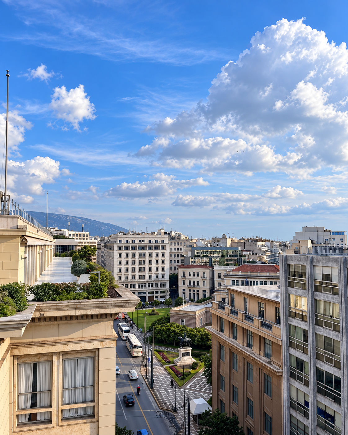Panoramic view across central Athens featuring city architecture, surrounding mountains, and a bright blue sky.