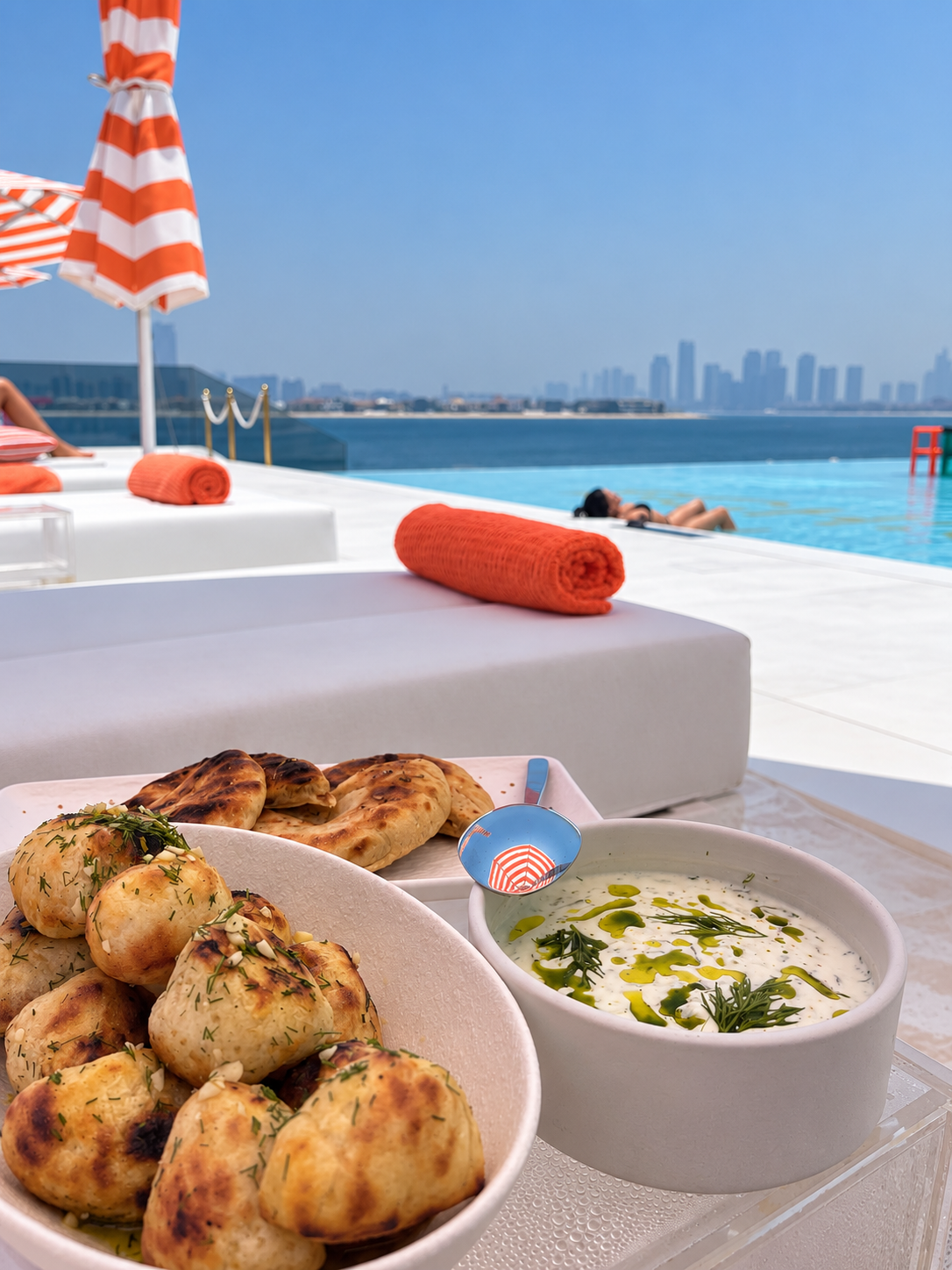 BCH CLB Beach Brunch Dishes Mediterranean-inspired dishes served poolside at BCH:CLB Dubai overlooking the water and Dubai skyline.