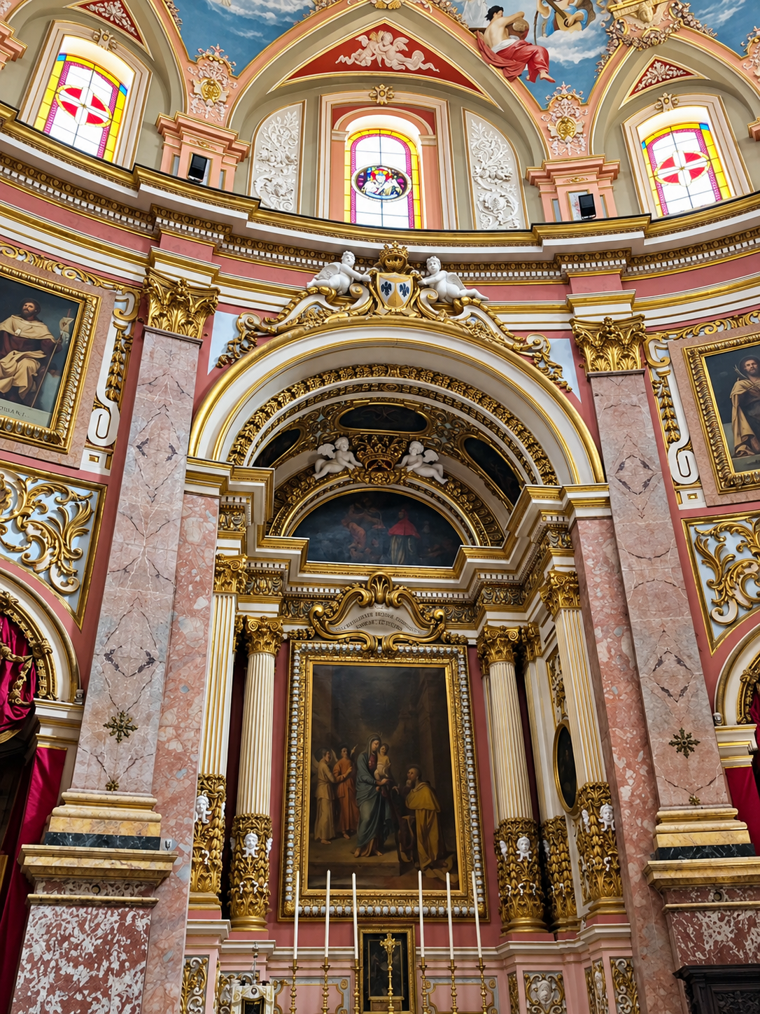 Ornate Baroque church interior in Mdina, Malta, featuring decorative stonework, artwork, and architectural details.