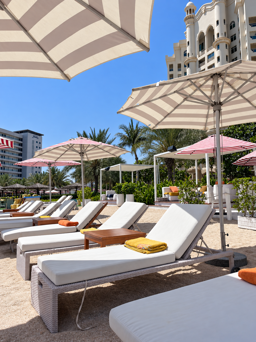 Peaches &amp; Cream Dubai beach club featuring sunbeds, pastel umbrellas, palm trees, and a relaxed waterfront setting.