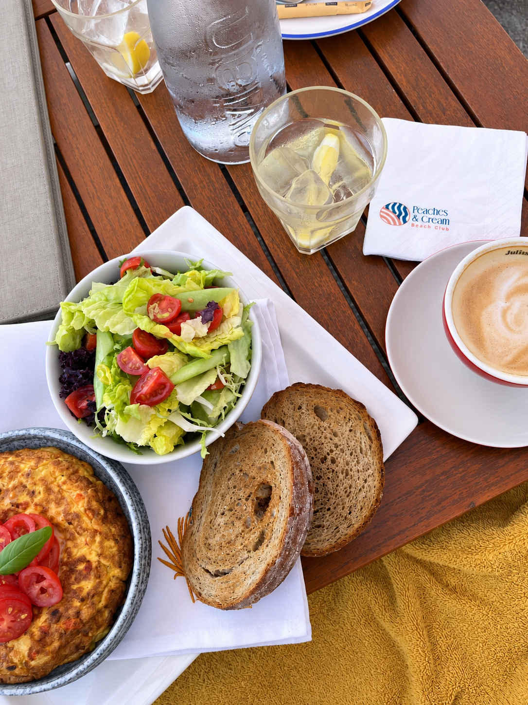 Breakfast at Peaches &amp; Cream Dubai featuring avocado salad, toast, coffee, and fresh juice by the beach.