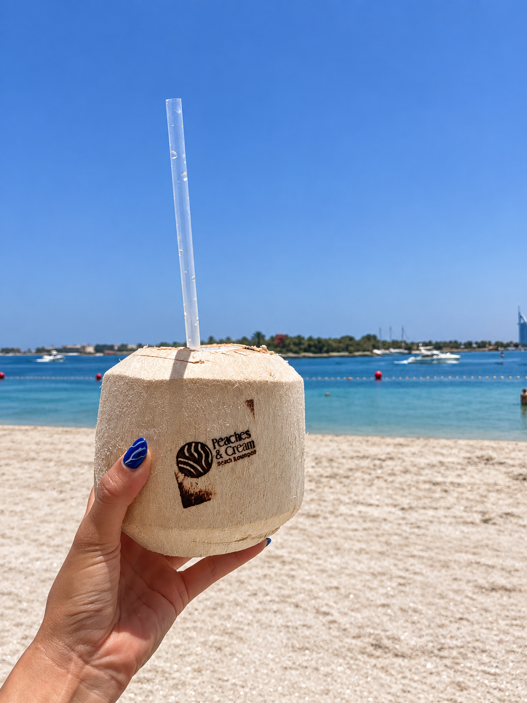 Fresh coconut drink overlooking the beach and blue Arabian Gulf waters at Peaches &amp; Cream Dubai.