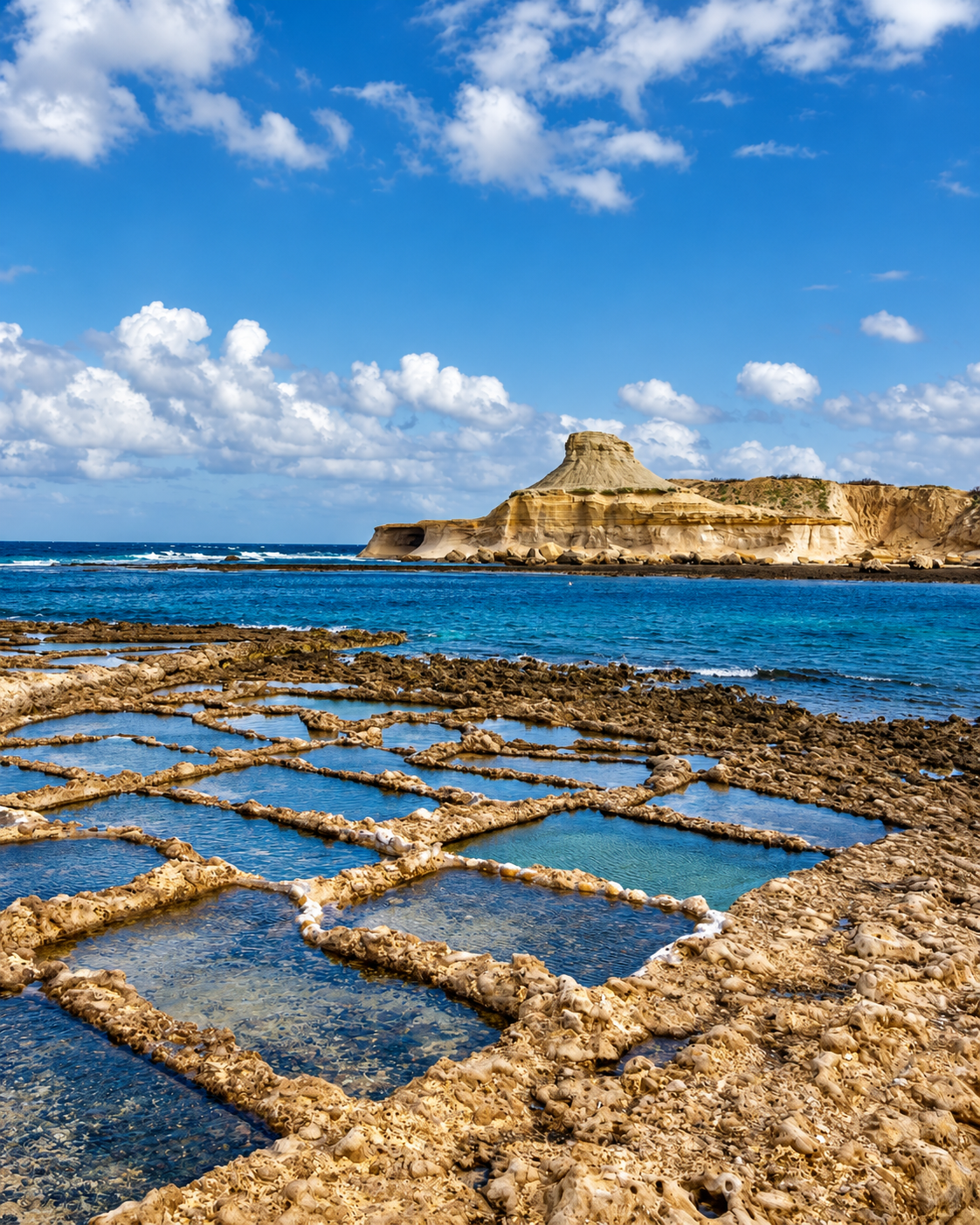 Traditional salt pans along the rocky coastline of Gozo, Malta, overlooking the Mediterranean Sea.