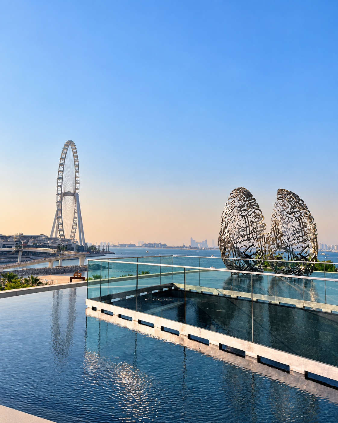 Scenic view of a waterfront area with a towering Ferris wheel and artistic metal sculptures  at The Address Marina