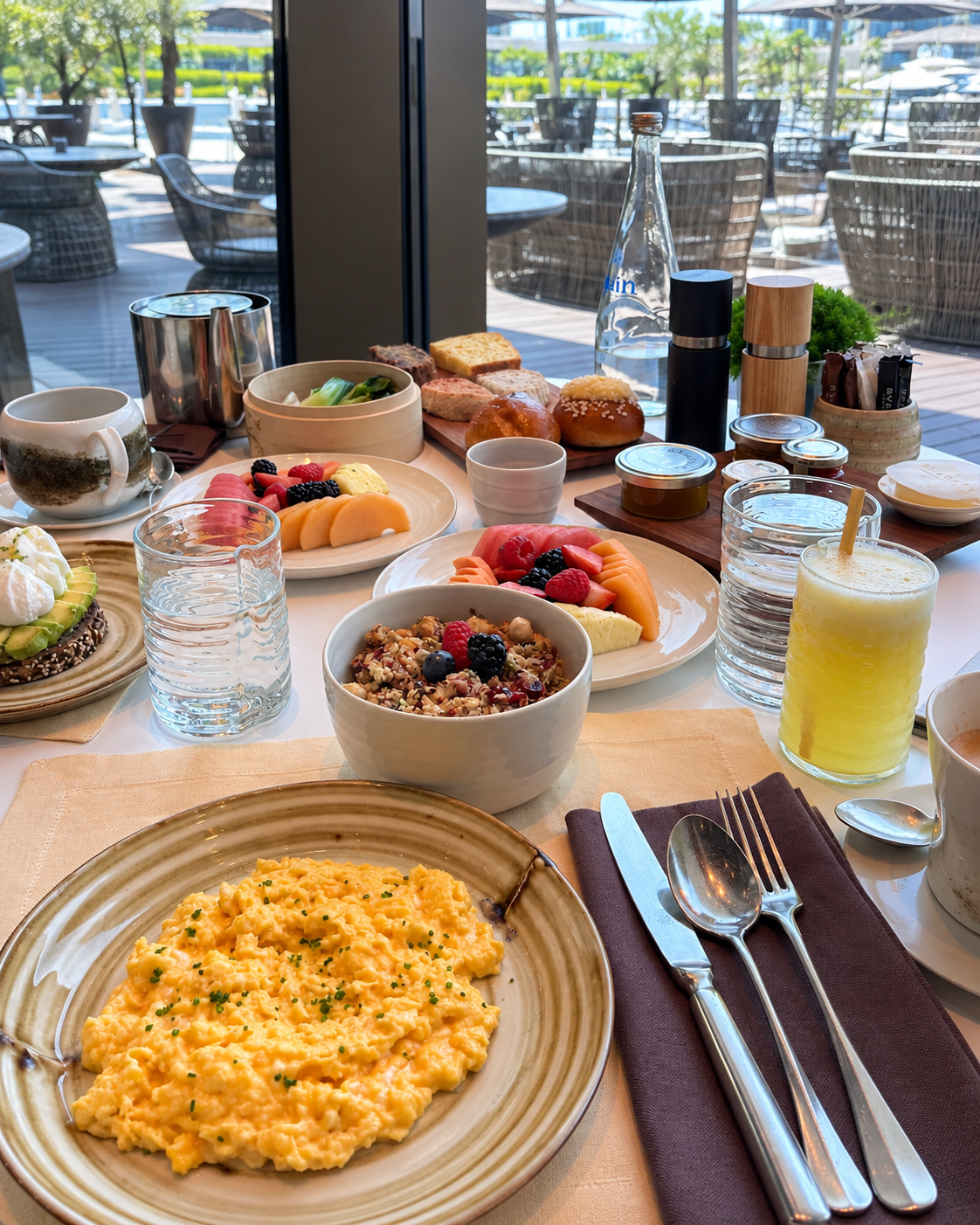 Bvlgari Resort Dubai Table Served Breakfast dishes at Bulgari Resort Dubai featuring eggs, fresh fruit, yogurt, coffee, and juice.