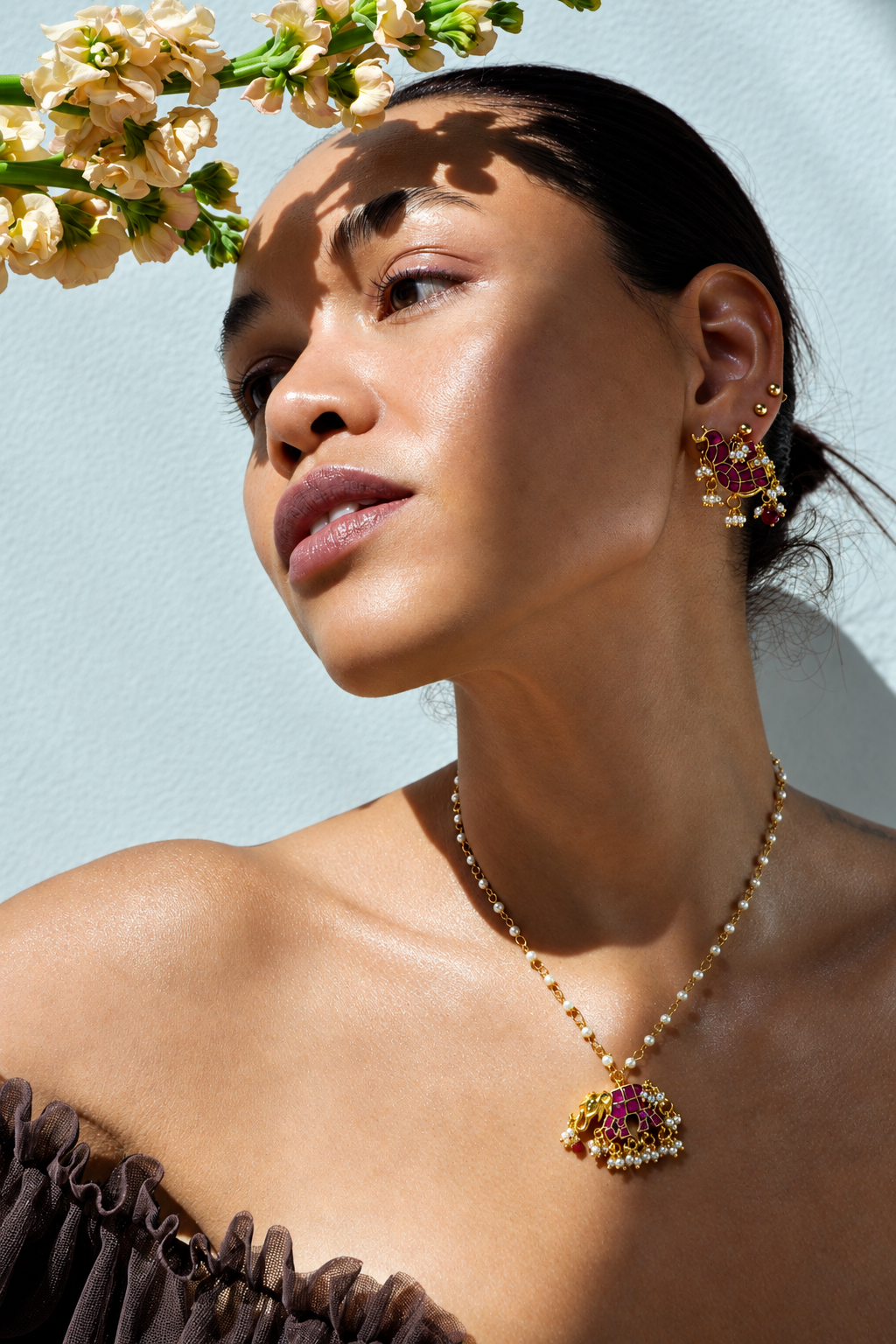 Rosi Ross wearing intricate jewelry in sunlight with flowers casting shadows from Tiramisu