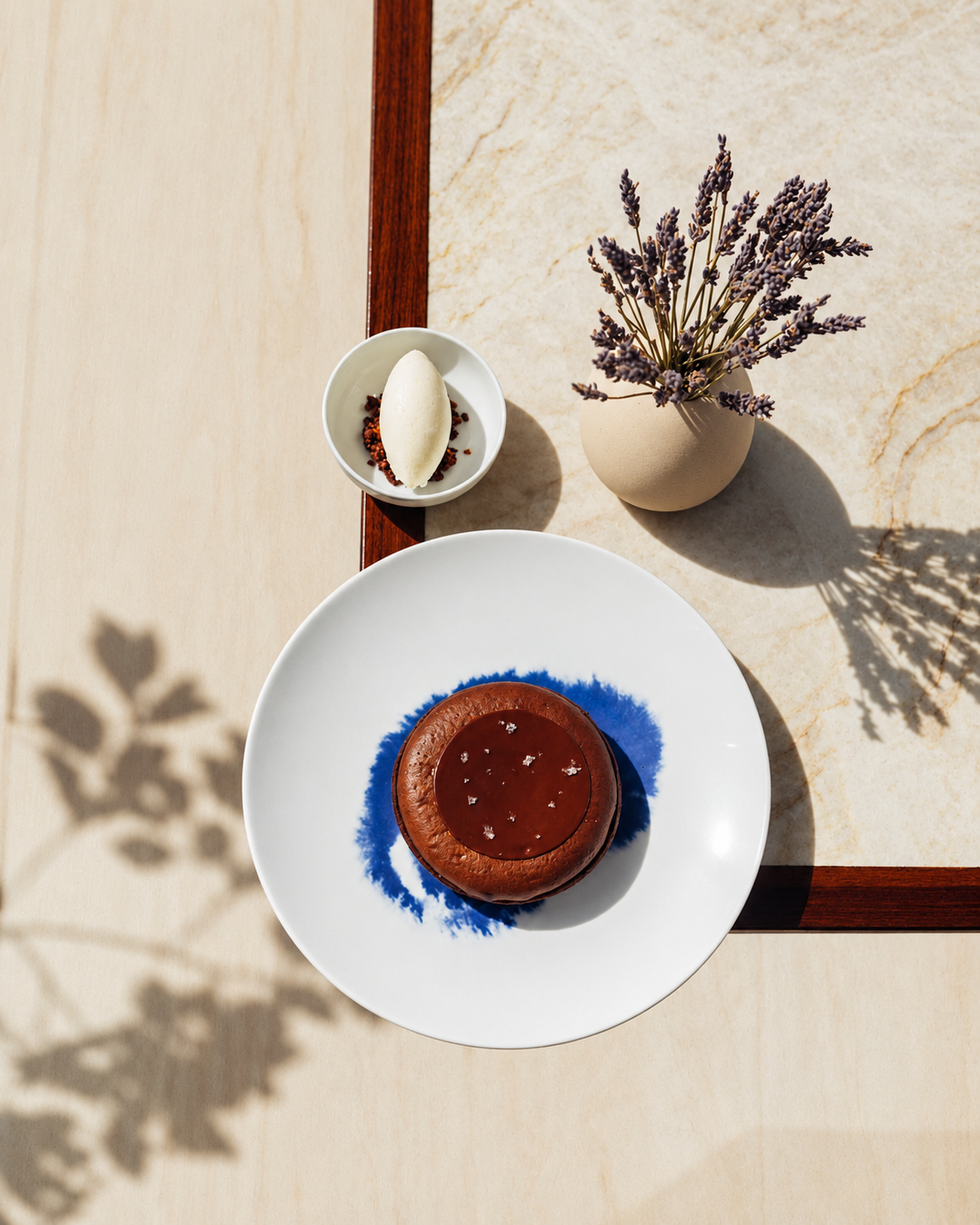 The Lana Dorchester Collection Desert Time Elegant dessert setup on a wooden table with chocolate cake, vanilla ice cream, and lavender in a vase at The Lana Dorchester Collection