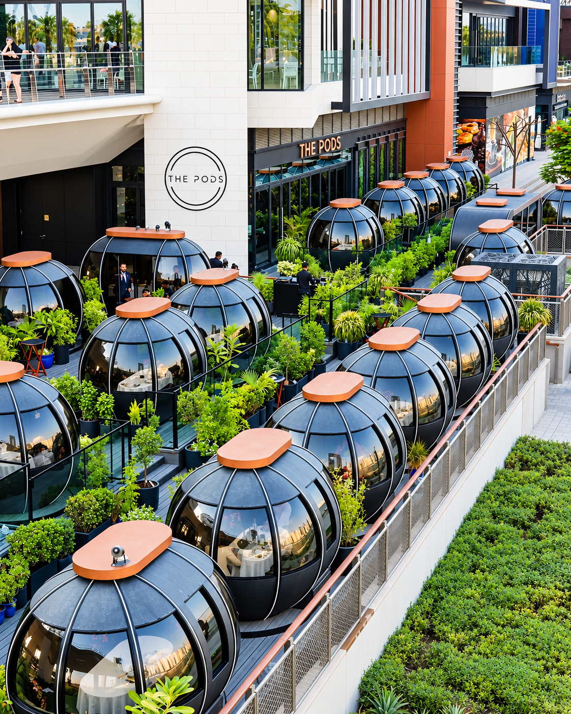 Futuristic outdoor dining pods with private seating and lush greenery at an upscale restaurant overlooking a modern city.