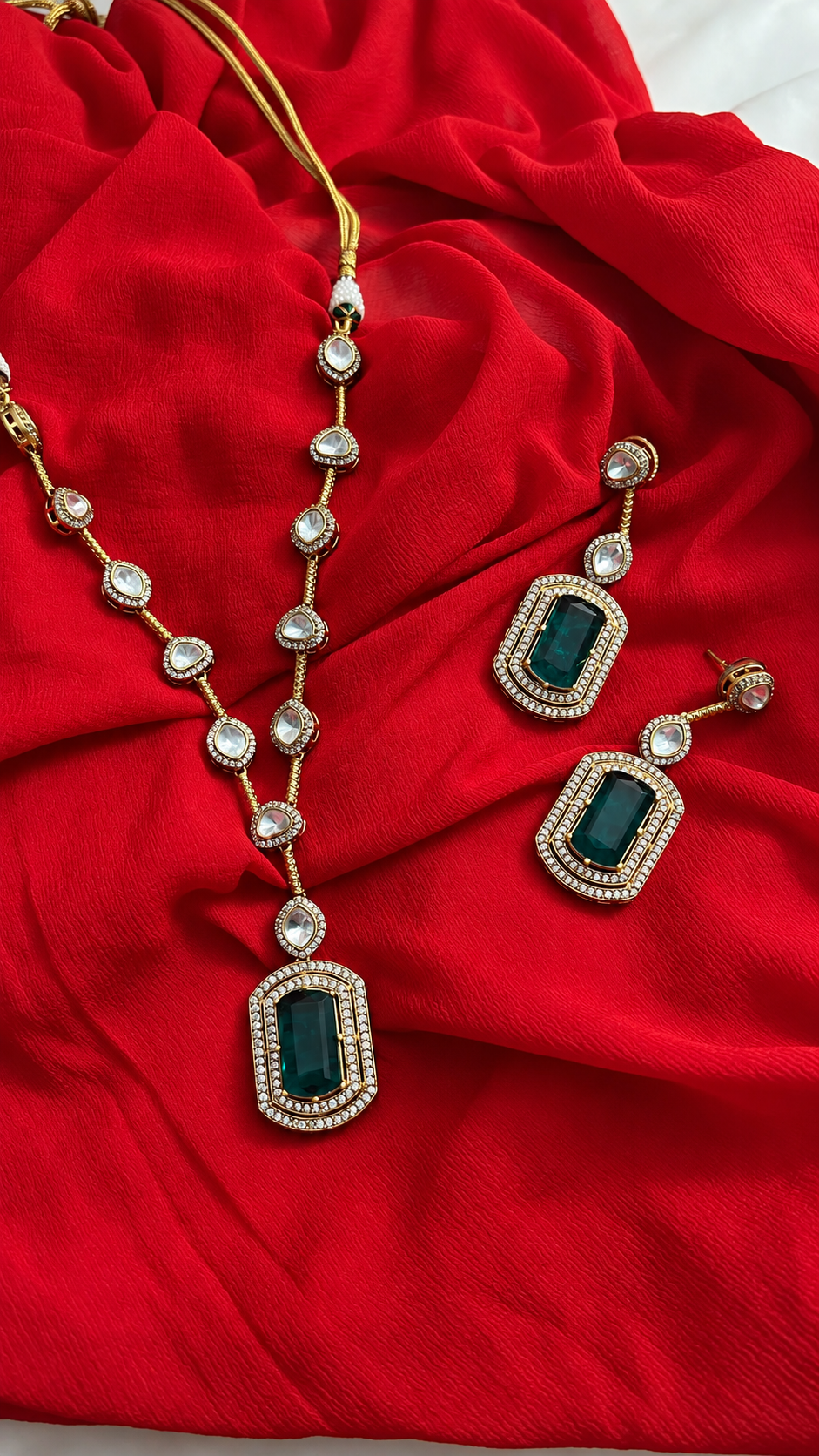 Elegant Jewelry Set with Green Stones from Tiramisu Elegant gold and crystal jewelry set on red fabric from Tiramisu