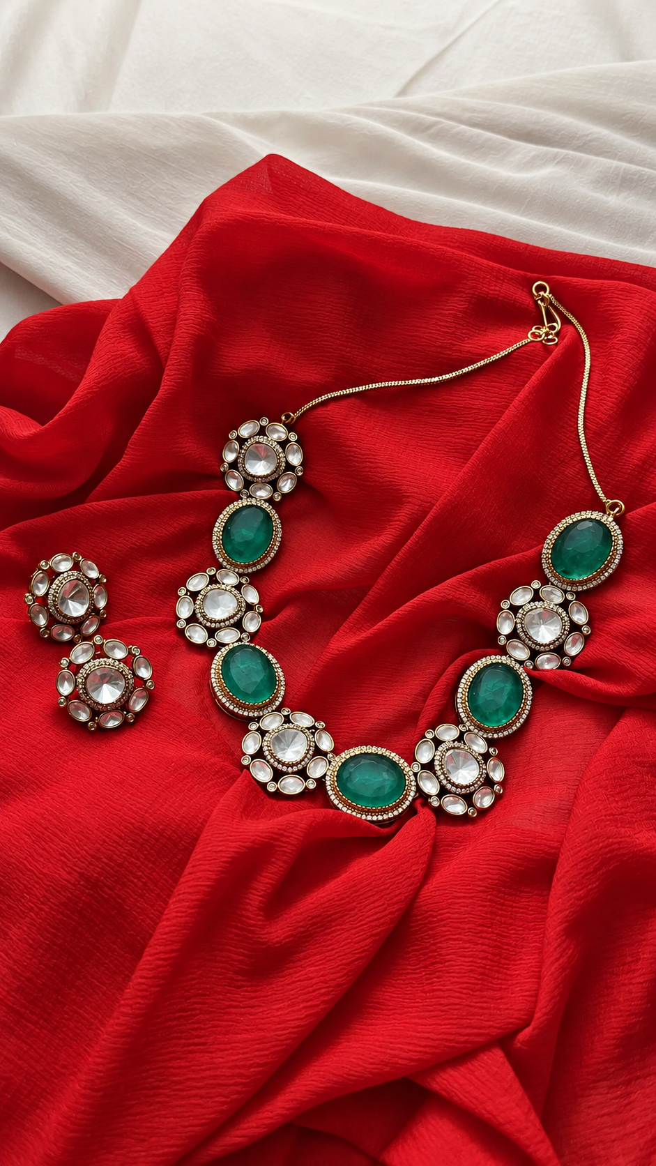 Emerald and Pearl Necklace Display from Tiramisu Elegant green and white gemstone necklace on red fabric from Tiramisu