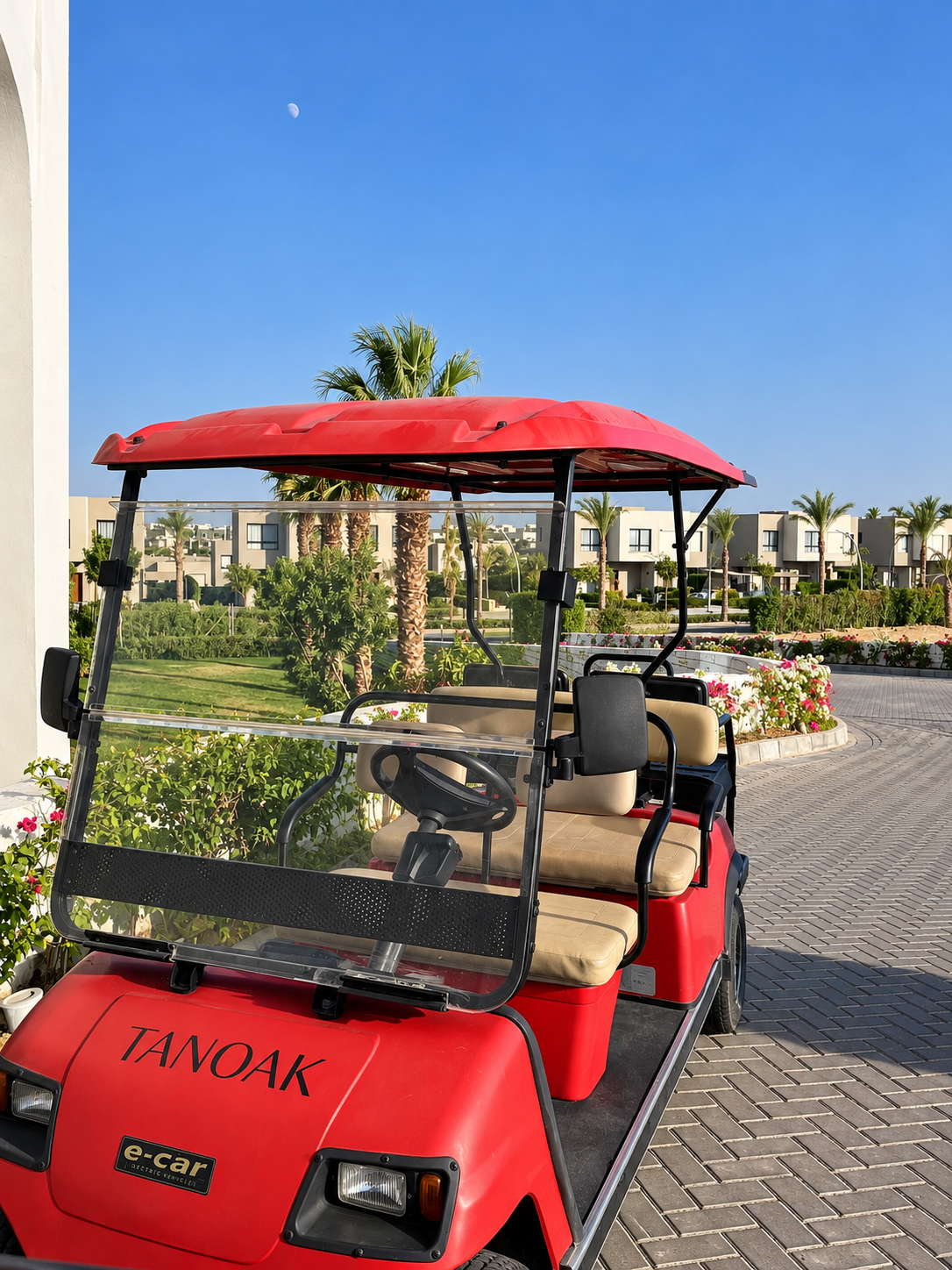 Red Golf Cart on Brick Path at Tanoak Resort in Ain Sokhna Red golf cart parked on a sunny brick-paved path with residential buildings in the background and a clear blue sky above at Tanoak Resort in Ain Sokhna