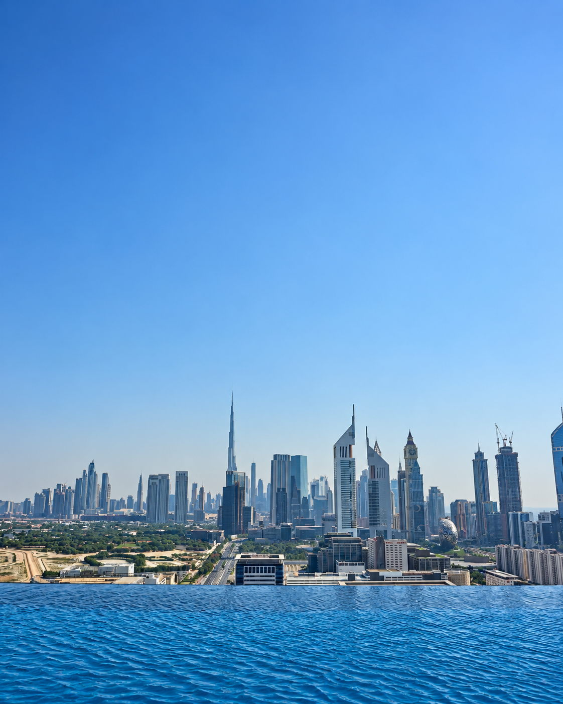 Dubai cityscape with Burj Khalifa in view from rooftop pool under clear blue sky.