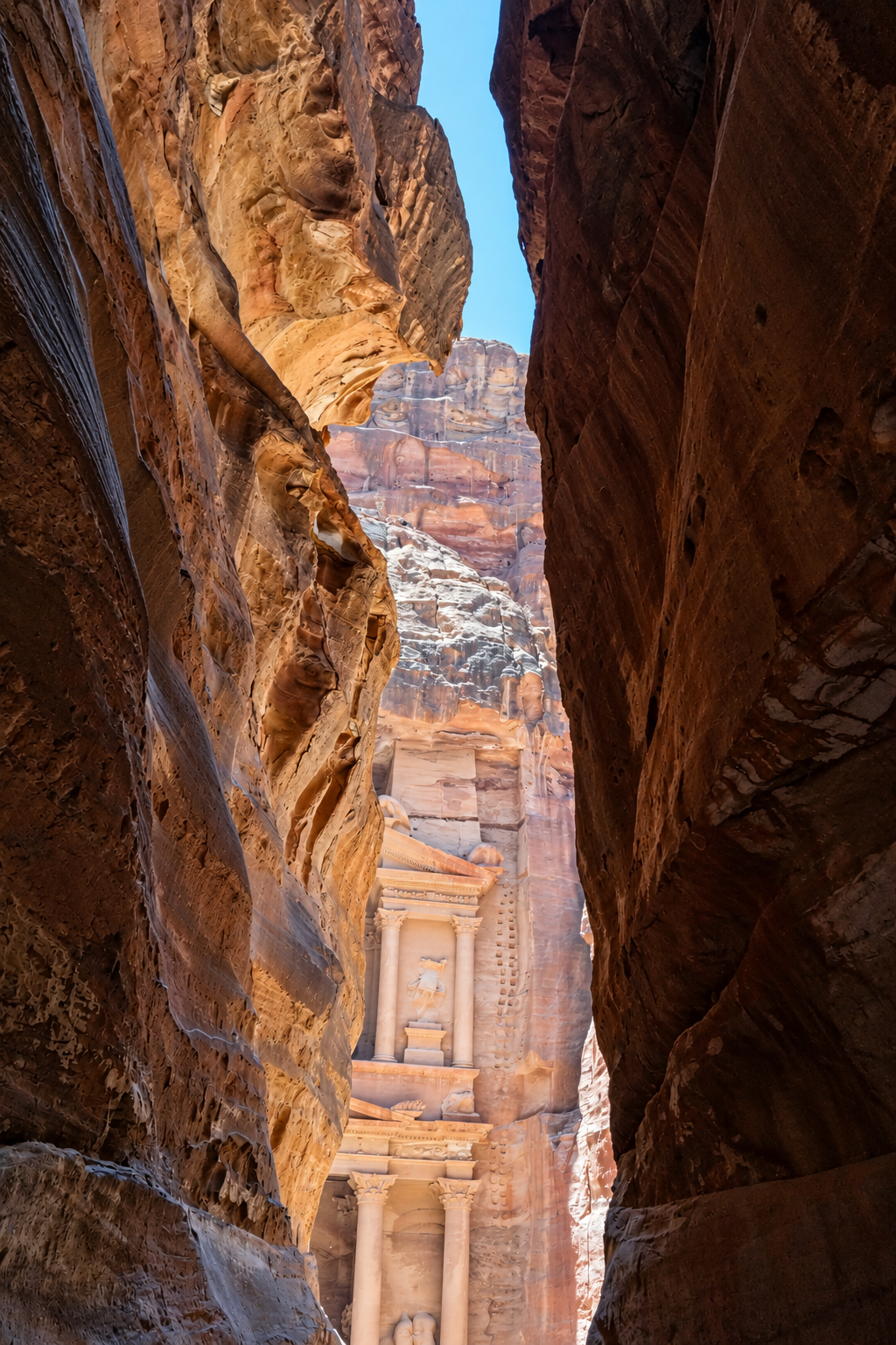 The Treasury of Petra viewed through narrow rock canyon walls.