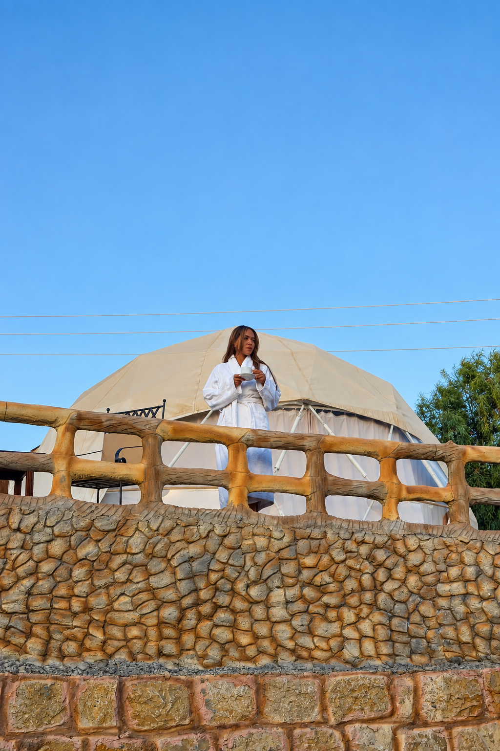 Rosi Ross Petra Seven Wonders Hotel And Domes Person standing on a stone terrace with a dome tent in the background and a clear blue sky at Seven Wonders Hotel