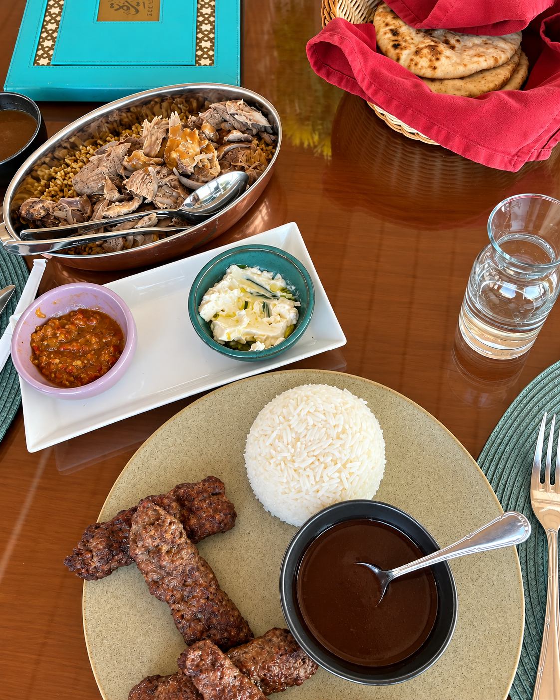 Traditional Egyptian meal with rice, lamb dish, flatbreads, and spicy dip.