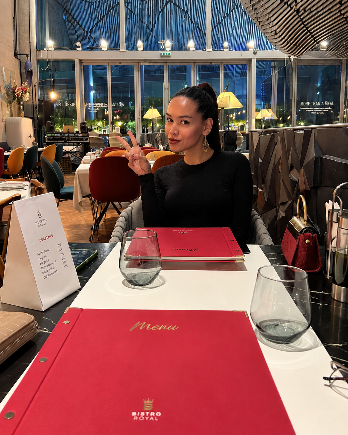 Casual Dining at Bistro Royal Design District Rosi Ross sitting in stylish restaurant with red menu folders and dim lighting at Design District