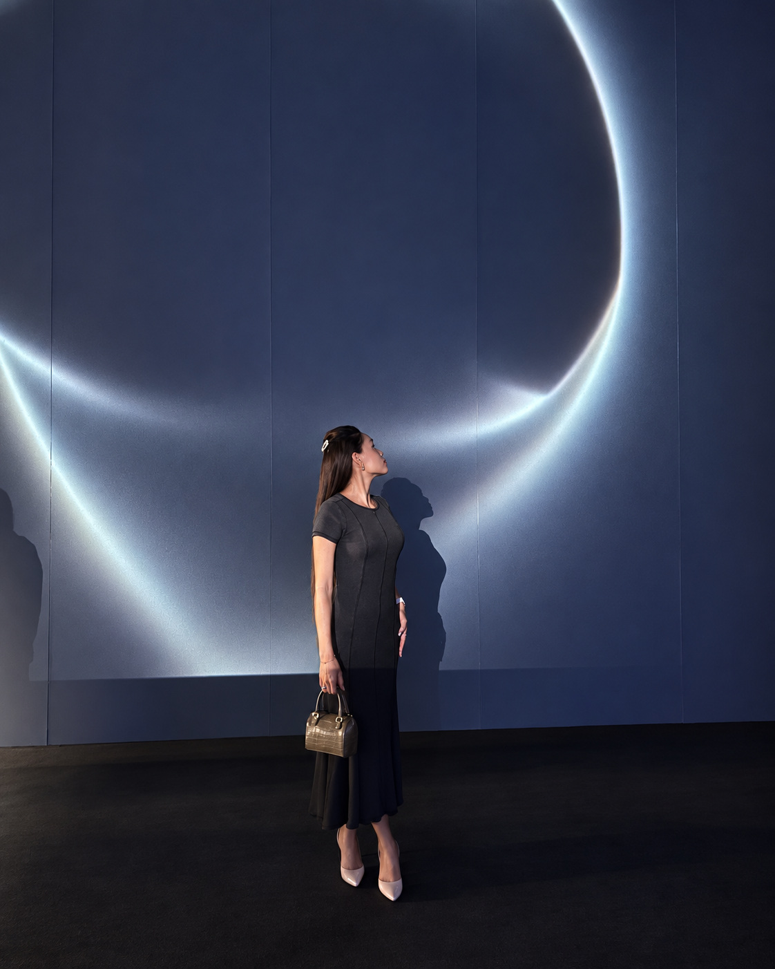 Rosi Ross in Elegant Grey Dress at Dubai Fashion Week Rosi Ross standing against a blue illuminated backdrop at Dubai Fashion Week