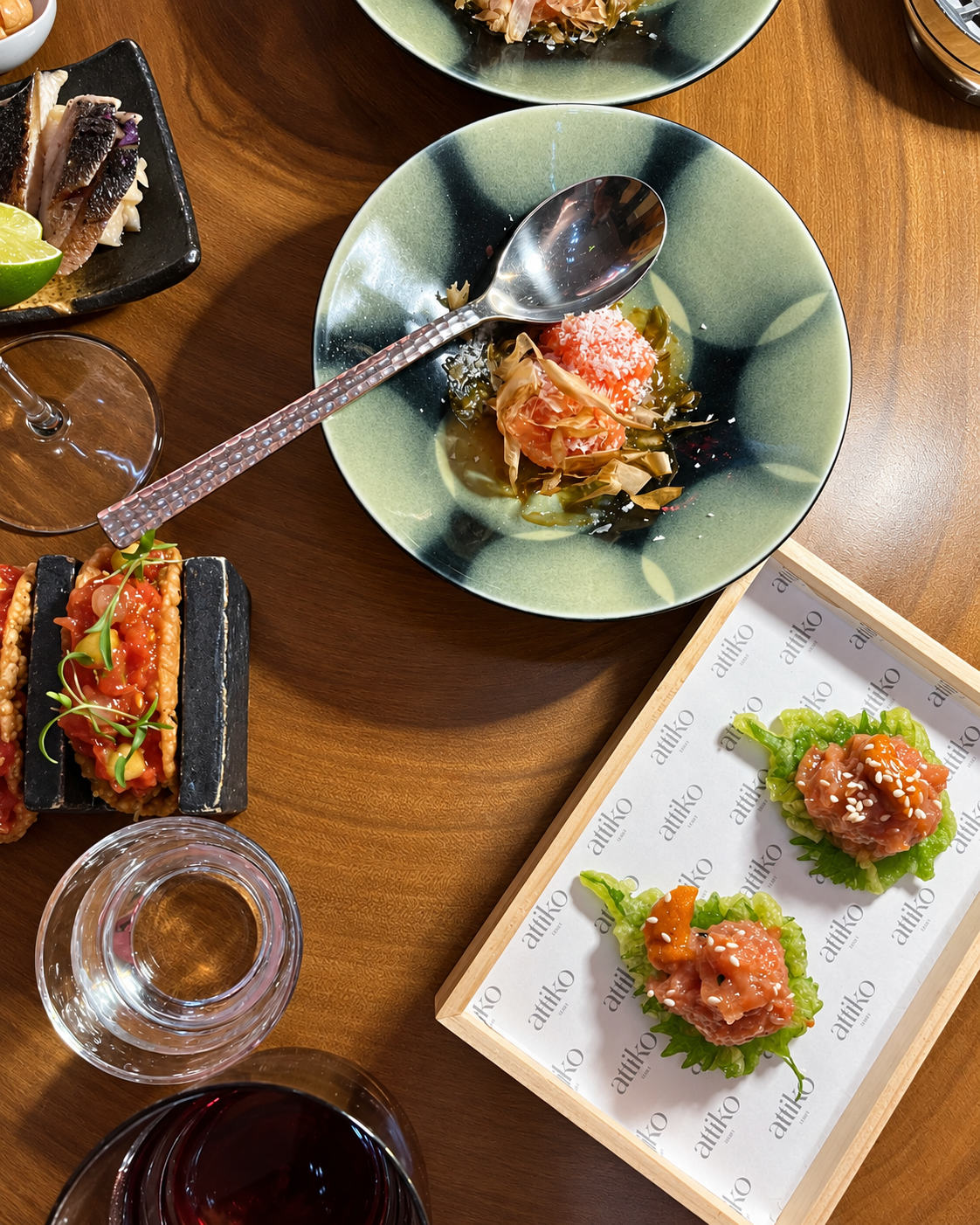 Izakaya Dining Experience at ATTIKO Dubai Elegant fine dining plated dishes featuring seafood and garnishes on wooden table at at ATTIKO Dubai