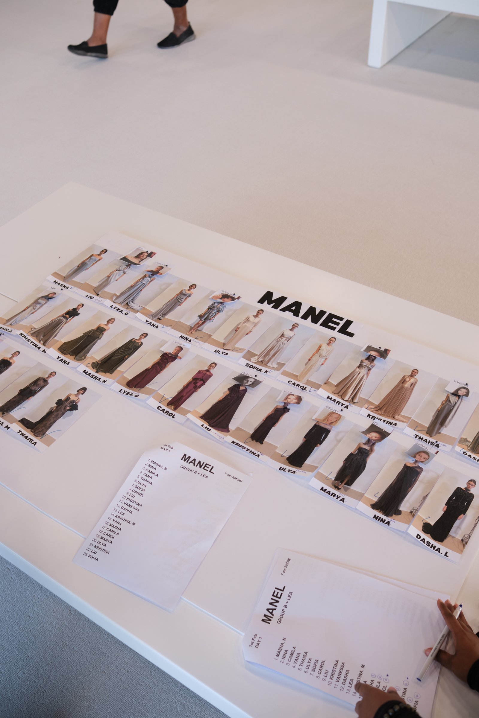 Overhead view of a fashion show lineup, featuring small photos of models in gowns and a list of names for a show titled "MANEL".