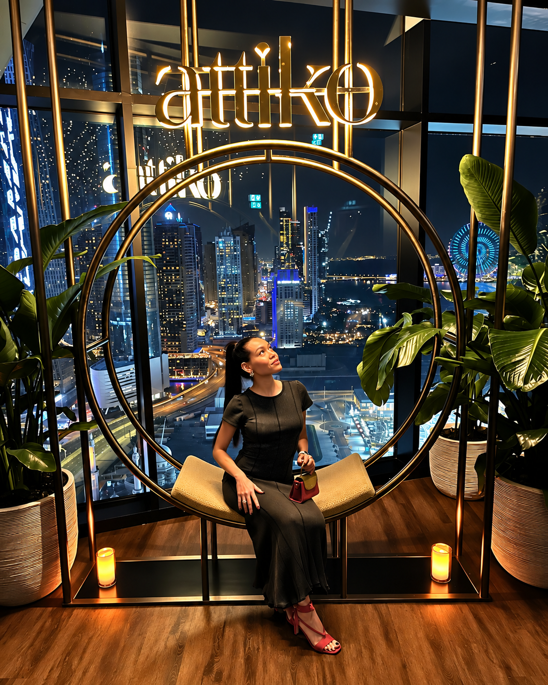 Rosi Ross in Neon-Lit Modern Window Installation at Attiko Dubai Rosi Ross in black outfit sitting within circular gold neon frame with cityscape view and illuminated plants at Attiko Dubai