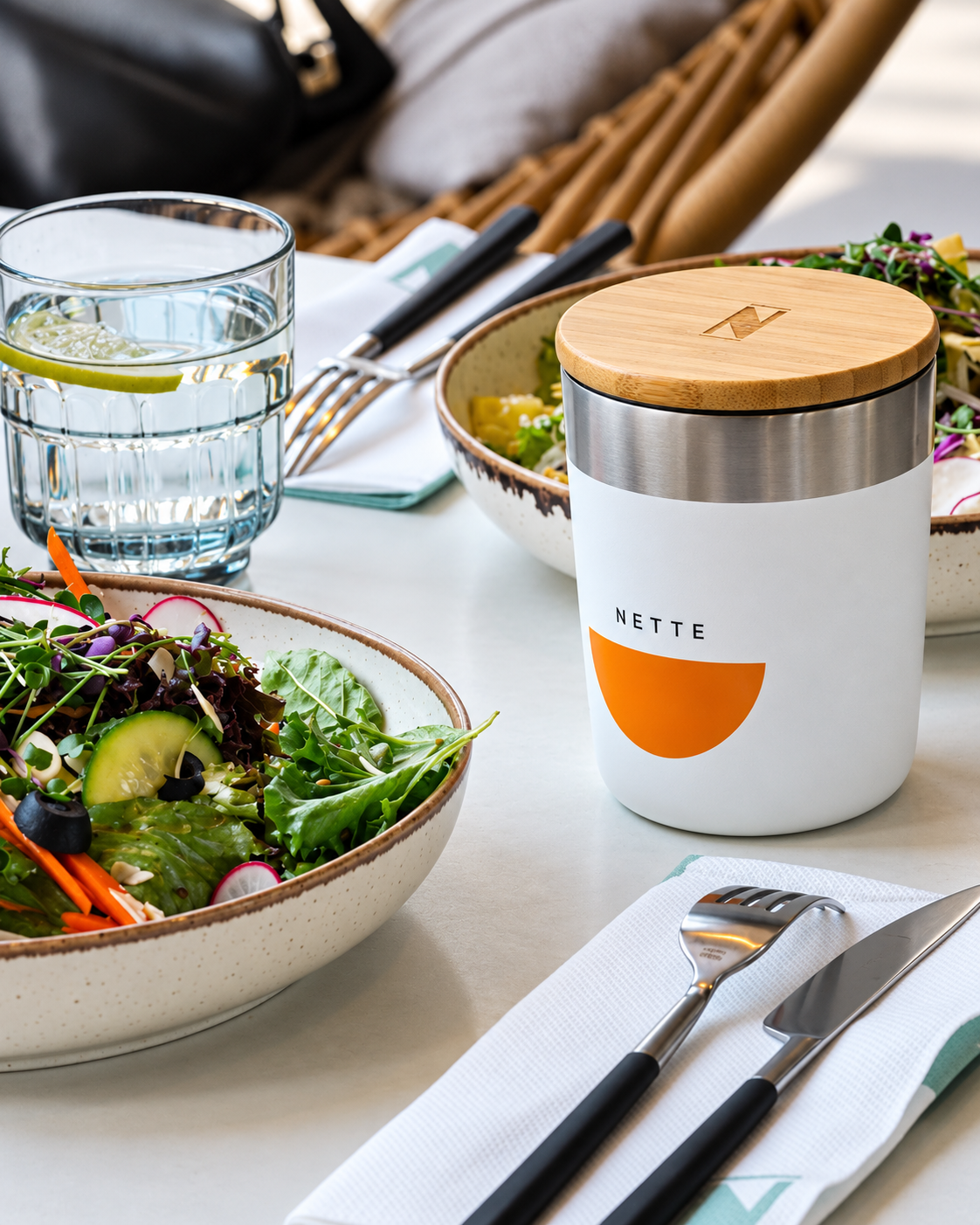 Modern Table Setting with Fresh Salad from NETTE Al Barari Dubai Modern table setting with fresh salad bowl, water glass, and white ceramic jar with wooden lid labeled NETTE