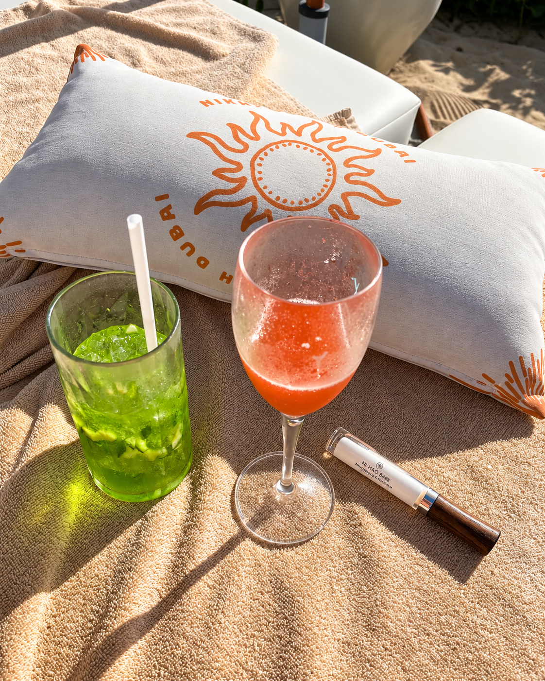Relaxing Drinks and Sun at Nikki Beach Dubai Two colorful drinks, a red one in a wine glass and a green one with a straw, next to a white pillow at Nikki Beach
