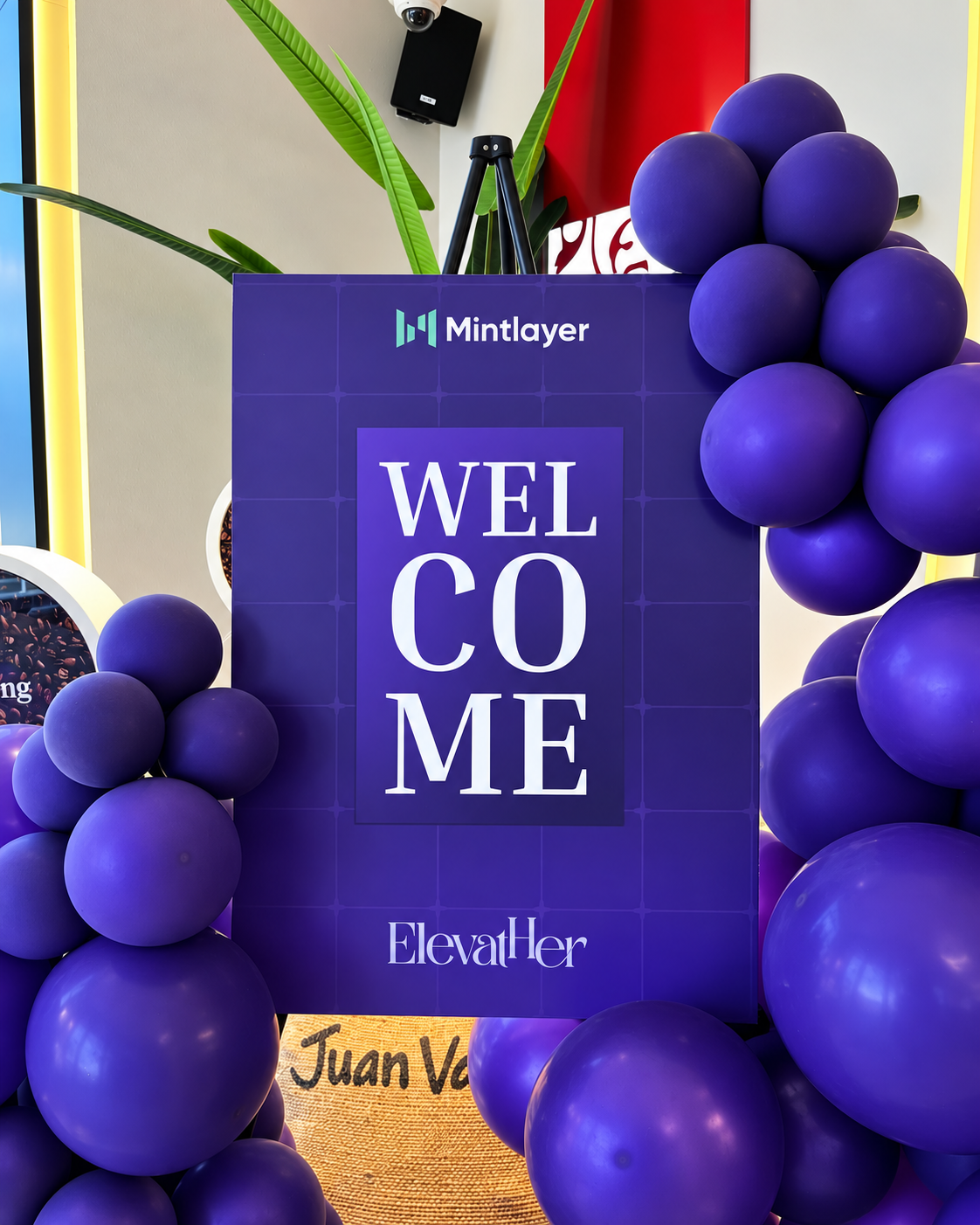 Rosi Ross As Guest at ElevateHer Event in Dubai Purple "Welcome" sign with Mintlayer and Elevaltier branding surrounded by purple balloons at event