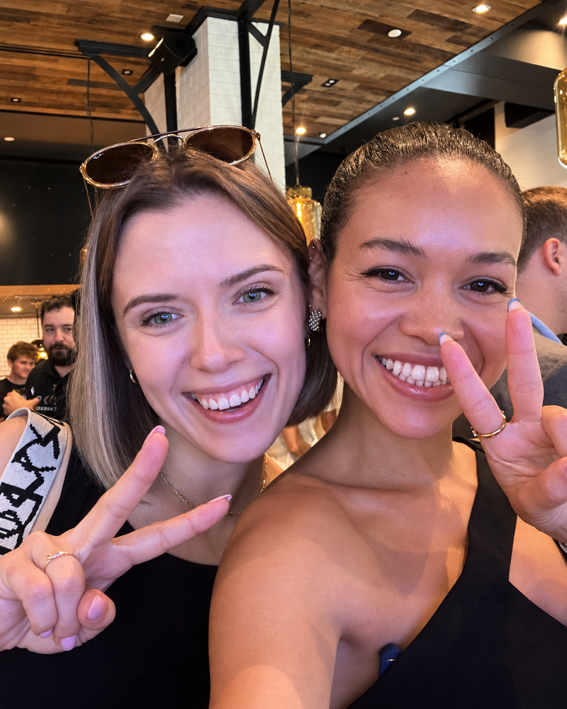 ElevateHer in Dubai making peace signs at an indoor event venue with warm lighting
