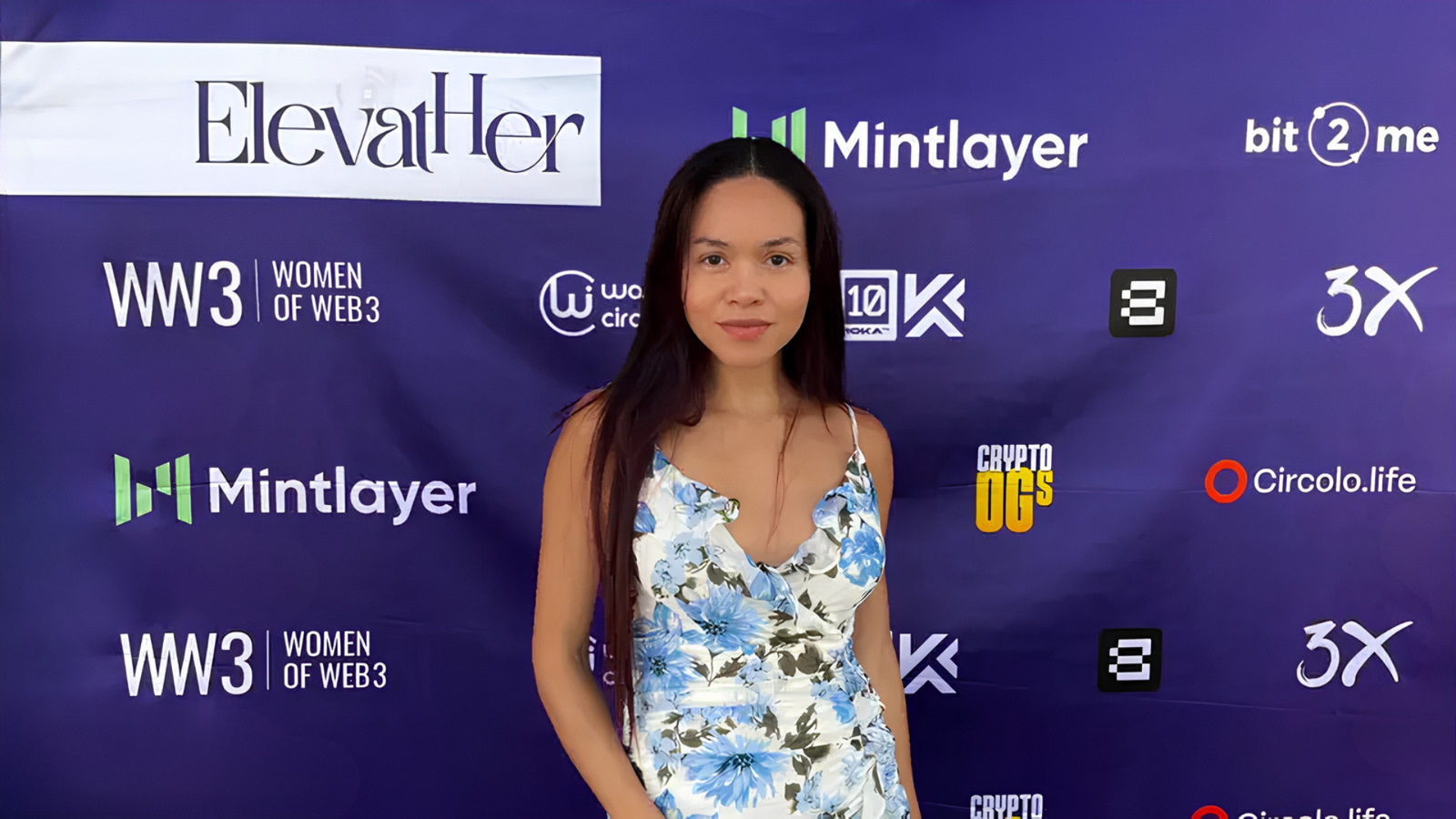 Rosi Ross standing in front of a branded banner at a Web3 and blockchain event during TOKEN2049 Dubai 2025 in Dubai, highlighting the city’s role in blockchain infrastructure, digital finance, and the global Web3 ecosystem.